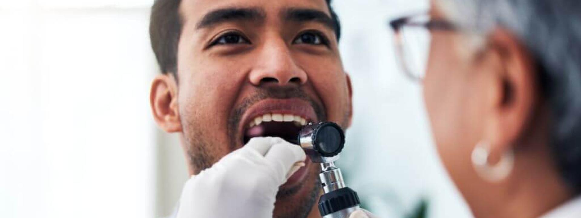 Dentist performing oral cancer screening on a male patient